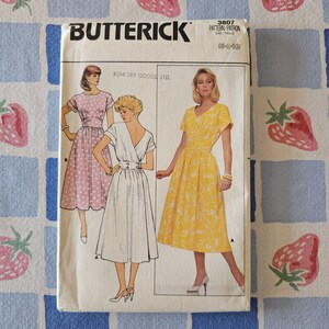 May include: A Butterick 3807 sewing pattern envelope for sizes 6-8-10. The front features illustrations of three dress variations: a polka-dot dress, a solid white dress with a buttoned waist, and a yellow dress with a white floral print.