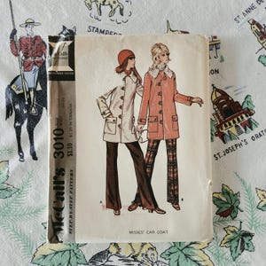 Könnte beinhalten: Ein Vintage-Schnittmusterumschlag von McCall's 3010 für einen Automantel. Die Vorderseite zeigt Illustrationen von zwei Figuren in langen Mänteln mit Pelzkragen, einer in Creme und einer in Koralle, kombiniert mit dunklen Hosen und karierten Hosen.