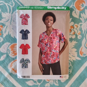 Puede incluir: Patrón de costura Simplicity S8949 D5 con una mujer con una blusa rosa floral. El patrón incluye ilustraciones de diferentes estilos de blusas. El rango de tallas del patrón es U.S. 4-12. El logotipo de Simplicity y el texto "Since 1927" son visibles.