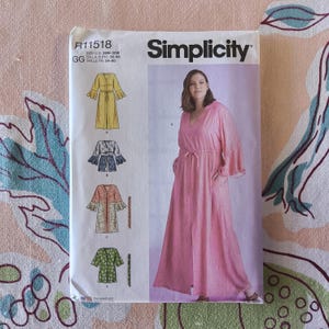 May include: Simplicity sewing pattern R11518 for a long, flowing dress with a V-neck and pockets. The pattern includes multiple design options, with illustrations of the finished garments in yellow, blue, coral, and green. The size range is 26W-32W.