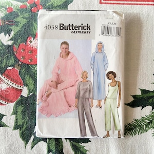 May include: A Butterick sewing pattern packet, featuring the number 4038 and the text "FAST & EASY." The packet displays illustrations of loungewear sets, including a pink hooded robe, a blue hooded dress, and gray and green two-piece outfits. Sizes XS, S, and M are indicated.