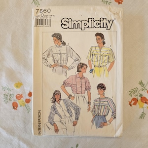 May include: A Simplicity sewing pattern envelope, number 7560, size O (12+14+16). The front features illustrations of five variations of a button-down shirt with different sleeve lengths, collar styles, and striped or solid fabric patterns.