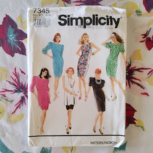 Puede incluir: Un patrón de costura Simplicity vintage, talla K5 (8-16), con ilustraciones de varios diseños de vestidos. El paquete del patrón es blanco con el logotipo de Simplicity y los detalles del producto. El fondo es una tela floral.