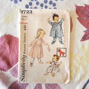 May include: Vintage Simplicity printed pattern for toddler size 3. The pattern features illustrations of children's clothing designs, including a coat, pajamas, and a dress. The pattern number is 3723.