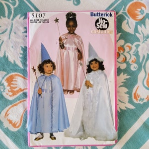 Puede incluir: Un patrón de costura vintage para un disfraz de hada sin coser. El patrón es para las tallas 5107 e incluye instrucciones para hacer un disfraz de hada rosa, azul y blanco. El patrón es de Butterick.