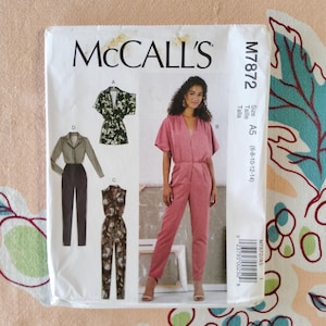 May include: A McCall's sewing pattern, M7872, featuring illustrations of jumpsuits. The pattern includes a pink jumpsuit with short sleeves, a green floral jumpsuit, and a long-sleeved jumpsuit. Size A5 (6-8-10-12-14).