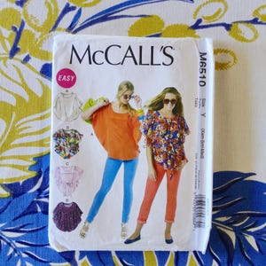 Puede incluir: Un sobre de patrón de costura McCall's blanco con ilustraciones de tops de mujer. El sobre tiene el logotipo de McCall's y el número de patrón M6510. La palabra "EASY" está en un círculo rosa. La talla es Y (Xsm-Sml-Med).