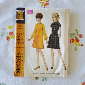 May include: Vintage McCall's printed pattern for Misses' dresses in two versions. The pattern features illustrations of two dresses: a yellow dress with long sleeves and a black and white checkered dress. The pattern size is 10, bust 82.5 cm.