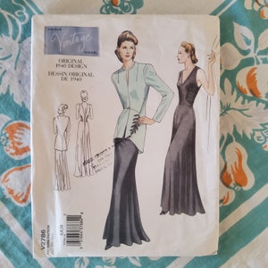 May include: Vintage sewing pattern for a 1940s dress. The pattern shows two women wearing long, flowing gowns. One gown is a light blue color with a jacket, and the other is a dark gray color. The pattern is titled "Vogue Vintage Model Original 1940 Design Dessin Original De 1940".