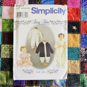 May include: A Simplicity sewing pattern envelope 9021 titled Fairy Tales from Around the World by Lucille Gamas. The cover displays illustrations of children wearing a pink dress, a white smocked romper, and a dark jacket with white trousers.
