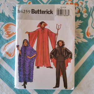 May include: Butterick B4259 sewing pattern featuring illustrations of three Halloween costumes: a red devil robe, a purple hooded cloak, and a black cape with red lining. The pattern includes sizes XS, S, and M.