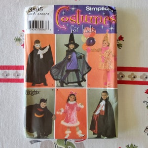 May include: A Simplicity sewing pattern for children's costumes. The pattern includes five different costumes: a vampire, a witch, a jester, a cat, and a bat. The pattern number is 3595 and the sizes are 3, 4, 5, 6, 7, and 8.