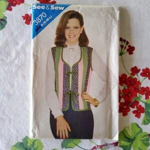 May include: A vintage sewing pattern for a vest with a tie closure. The pattern is for sizes S-M-L and is from the brand See & Sew. The pattern number is 3870.