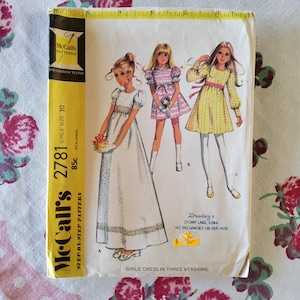 May include: Vintage McCall's sewing pattern for a girl's dress in three versions. The pattern is for size 10 and includes step-by-step instructions. The pattern is yellow with black text and illustrations of three girls wearing different versions of the dress.