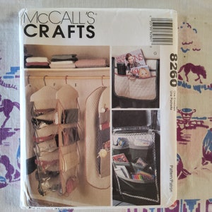 May include: A sewing pattern for a hanging organizer with multiple pockets. The pattern is for a one-envelope, one-pocket organizer. The pattern is from McCall's Crafts and the pattern number is 8260.