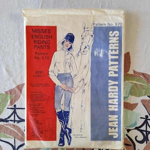 May include: Vintage sewing pattern for Misses' English riding pants. The pattern packet features an illustration of a woman in riding attire with a horse. The text includes "Misses' English Riding Pants" and "Jean Hardy Patterns".