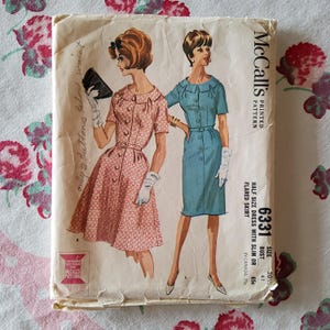 Puede incluir: Patrón de costura vintage McCall's para un vestido de media talla con falda ajustada o acampanada. El número del patrón es 6331 y la talla es 20 1/2, busto 41 o 65c. El patrón presenta dos ilustraciones de mujeres con el vestido, una en rosa y otra en azul.