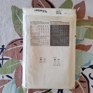 May include: Vintage Vogue sewing pattern for misses' pants and shorts. The pattern envelope is off-white with black text and illustrations. The pattern number is 8123. The envelope is slightly worn, with a floral background.