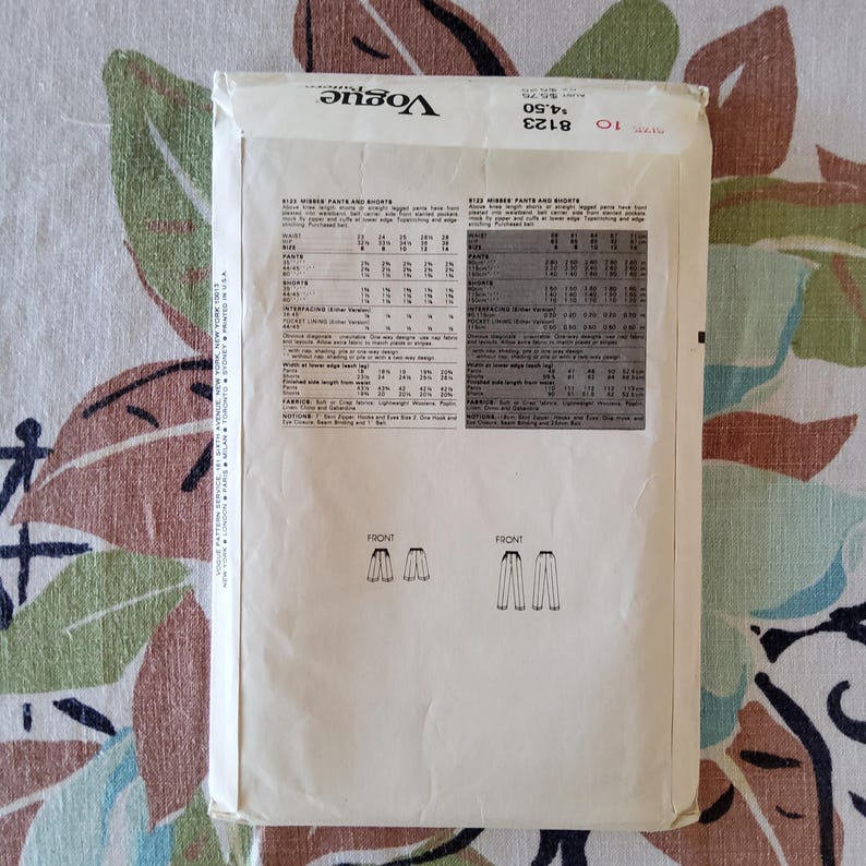 May include: Vintage Vogue sewing pattern for misses' pants and shorts. The pattern envelope is off-white with black text and illustrations. The pattern number is 8123. The envelope is slightly worn, with a floral background.