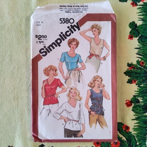 May include: Simplicity sewing pattern number 5380 for a women's top. The pattern includes five different styles of tops, including a sleeveless top, a short-sleeved top, and a long-sleeved top. The pattern is for sizes 14 and up.