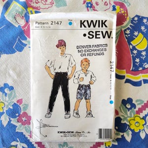 May include: A vintage Kwik Sew sewing pattern packet, pattern 2147, featuring illustrations of two children in casual outfits. The packet includes the text "Denver Fabrics No Exchanges or Refunds."