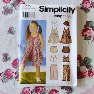 May include: Simplicity sewing pattern for girls' clothing, featuring a floral print dress, shorts, top, and pants. The pattern includes a photo of a girl wearing a dress made from the pattern. The package has the number 5540 and the words "easy-to-sew".
