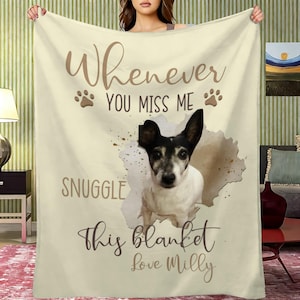 Op de afbeelding: Crèmekleurige deken met een hondenportret en de tekst "Whenever You Miss Me Snuggle This Blanket Love Milly" in bruin schrift. De hond is zwart en wit, met bruine pootafdrukken.