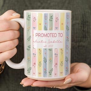 May include: A white ceramic mug featuring vertical pastel stripes in shades of pink, yellow, green, and blue, decorated with small floral and leaf motifs. The text reads PROMOTED TO Auntie Isabella est. 2027 in a mix of bold and script fonts.