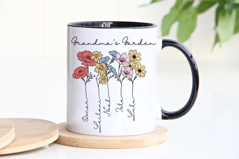 Pu&ograve; includere: Tazza in ceramica bianca con bordo e manico neri, con un design floreale con fiori rossi, gialli, blu e rosa. Le parole "Grandma's Garden" sono scritte sopra i fiori, con nomi sotto.