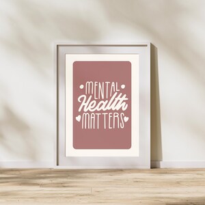 May include: A white framed print with a pink background and white text that reads "Mental Health Matters" with two small white hearts on either side of the text.