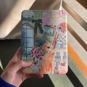 Könnte beinhalten: Eine dekorative Hülle mit einer skurrilen Illustration. Das Design zeigt einen Golden Retriever mit Blumen, eine gerahmte Landschaft, ein Fenster und einen schlafenden Welpen. Die Farbpalette umfasst Beige-, Grün-, Rosa- und Blautöne.