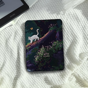 Puede incluir: Una funda negra para Kindle con una ilustración pixelada de un gato blanco caminando sobre una rama de árbol. El diseño incluye una escena de bosque con mariposas y el texto "earth trines".