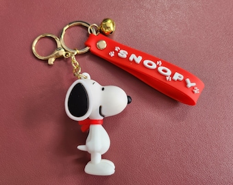 Encantador llavero de Snoopy: figura blanca de Snoopy con correa roja y timbre de seguridad.