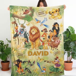 May include: A rectangular fleece blanket featuring a colorful print of various Lion King characters including Simba, Mufasa, Scar, Timon, Pumbaa, Zazu, and Rafiki. The design includes green foliage, yellow butterflies, and the text "DAVID" and "HAKUNA MATATA".