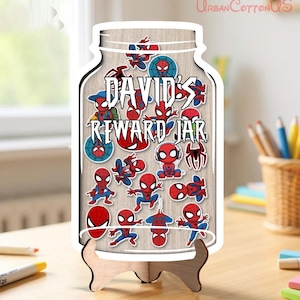 May include: A wooden reward jar shaped like a mason jar, featuring the text 'DAVID'S REWARD JAR' in a stylised font. The jar is filled with various colourful stickers of the superhero Spider-Man in different poses and is supported by a wooden stand.