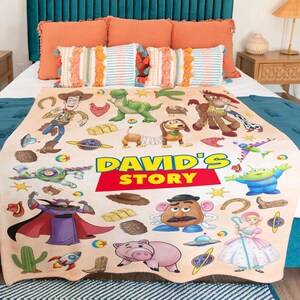 May include: A beige fleece blanket featuring a colorful print of Toy Story characters including Woody, Buzz Lightyear, Rex, Slinky Dog, Mr. Potato Head, and Bo Peep. The center displays the text DAVID'S STORY in bold yellow and red lettering.