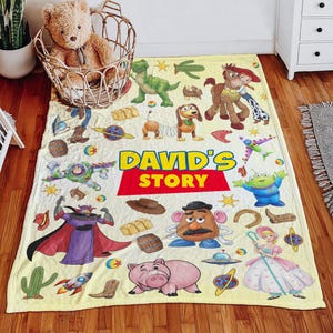 May include: A light yellow fleece blanket featuring various Toy Story characters including Buzz Lightyear, Woody, Jessie, Bullseye, Rex, Slinky Dog, Mr. Potato Head, Bo Peep, and Zurg, with the text DAVID'S STORY printed in large blue and red letters.