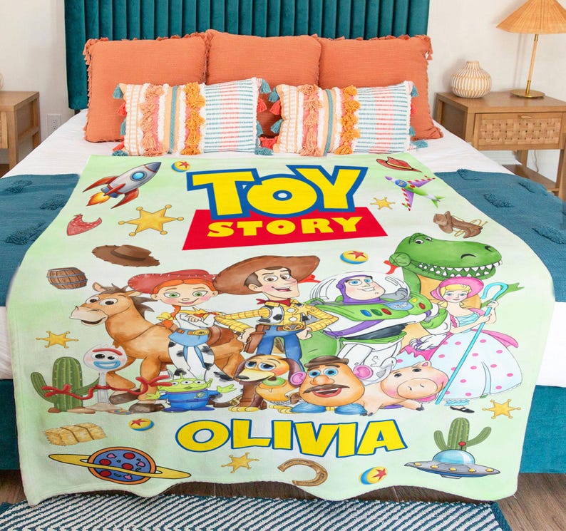 May include: A light green fleece blanket featuring the Toy Story logo, the name Olivia, and various characters including Woody, Buzz Lightyear, Jessie, Bullseye, Rex, and Mr. Potato Head, decorated with colorful space and western themed icons.