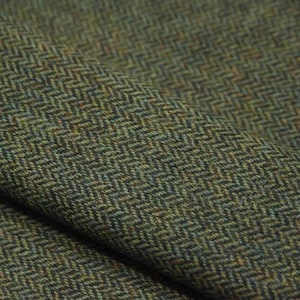 May include: Close-up of a folded fabric with a herringbone pattern. The fabric is a blend of green, brown, and blue hues, creating a textured appearance. The weave is tightly knit, suggesting a durable material suitable for apparel or upholstery.