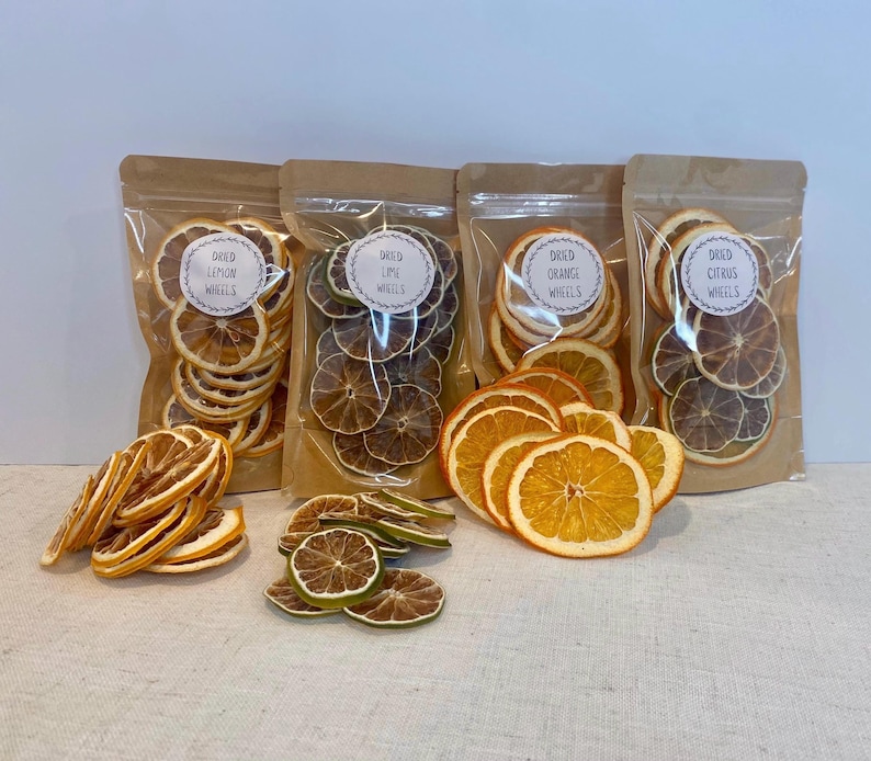 May include: Four clear plastic bags filled with dried citrus wheels, including lemon, lime, orange, and a citrus mix. Each bag has a label with the words "Dried Wheels". Some dried citrus wheels are outside the bags.