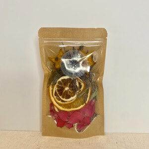 May include: A clear plastic bag filled with dried fruit and flowers. The bag is made of brown paper and has a white label with the text "My & Co. Creating Moments" on it.