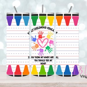 May include: A white tumbler with a design of colourful crayons and a handprint heart with the text "Early Childhood Education" and "If you think my hands are full, you should see my heart".