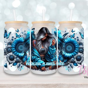 May include: Three frosted glass tumblers with lids and straws. Each tumbler features a design of a woman with blue angel wings, blue sunflowers, and butterflies. The text "FEARLESS. FLAWED. FREE" is printed on the front.