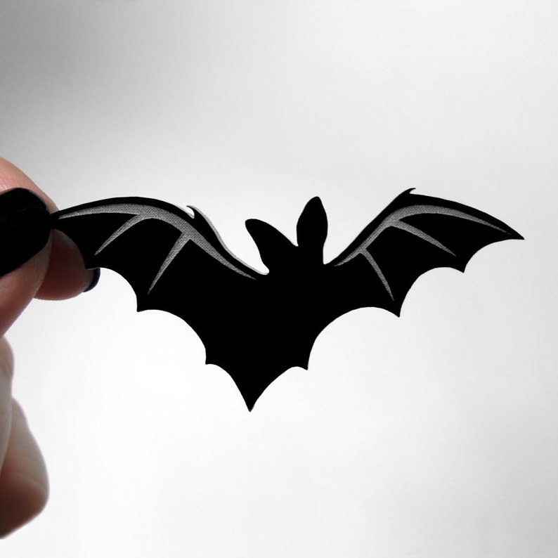 Close-up of oversized bat ring being held – engraved acrylic bat with elastic band setting, gothic Halloween costume jewelry.