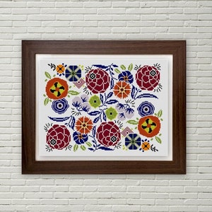 May include: A framed cross-stitch embroidery featuring a colorful floral design with red, orange, yellow, green, blue, and white flowers. The flowers are arranged in a symmetrical pattern on a white background.