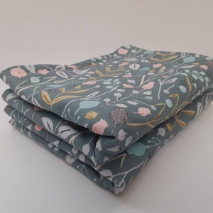 以下が含まれることがあります： 青、ピンク、黄色の花柄の布の正方形が4枚重ねられています。布は薄い青色の背景に白い花柄が描かれています。