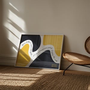 May include: Framed art print with a white border. The artwork features abstract yellow and black shapes with the quote "Your body is not a temple, it's an amusement park. Enjoy the ride." by Anthony Bourdain.