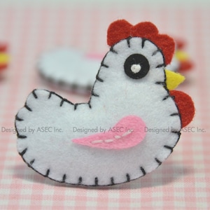 May include: A white felt chicken with red comb and wattle, a yellow beak, and a pink wing. The chicken is hand-stitched with black thread. The background is a pink and white checkered pattern. Designed by ASEC Inc.