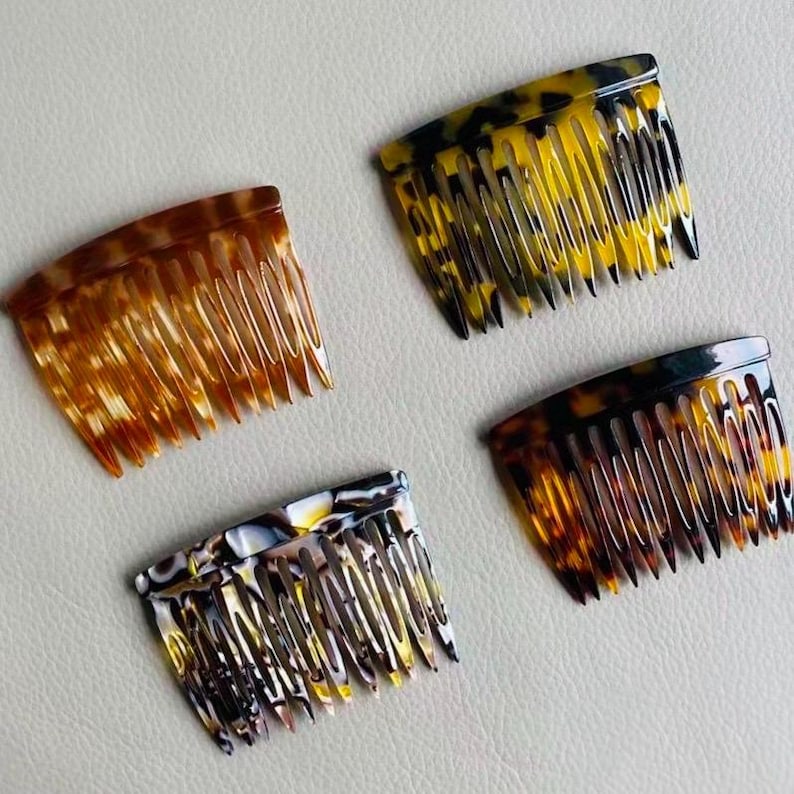 Puede incluir: Cuatro peines decorativos para el cabello en varios patrones de carey. Los peines son en tonos de marr&oacute;n, amarillo y negro. Cada peine tiene una parte superior curva y dientes espaciados uniformemente.