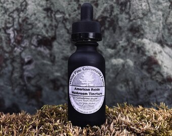 May include: A black glass bottle with a dropper top and a white label that reads "White Pine Community Farm American Reishi Mushroom Tincture Ganoderma tsugee contains: Reishi Mushroom & grain alcohol 1 fl oz (29ml)"